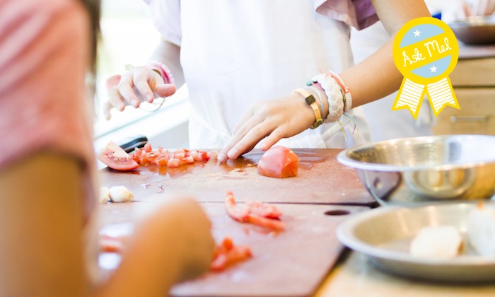 Two women cooking and chopping tomatoes in the kitchen