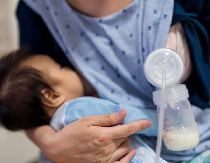 Woman breastfeeding and pumping at the same time