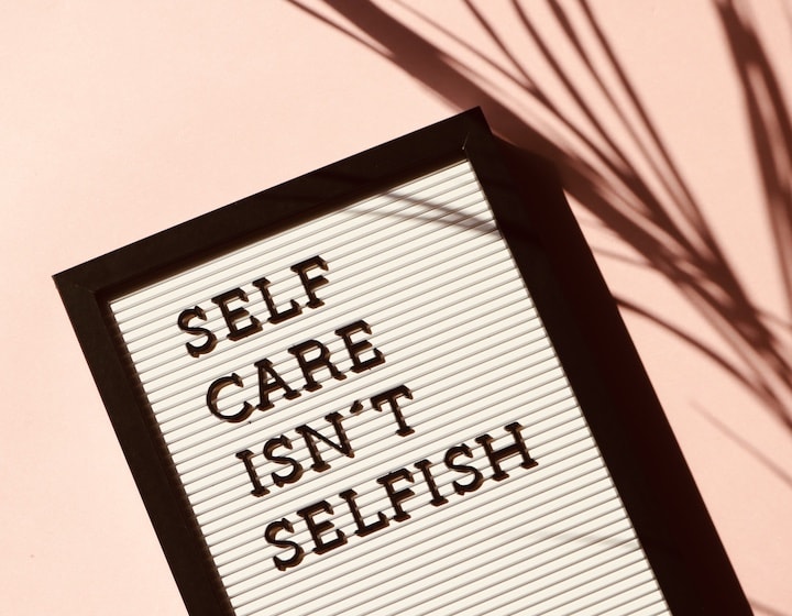 Self care isn't selfish sign on pink background