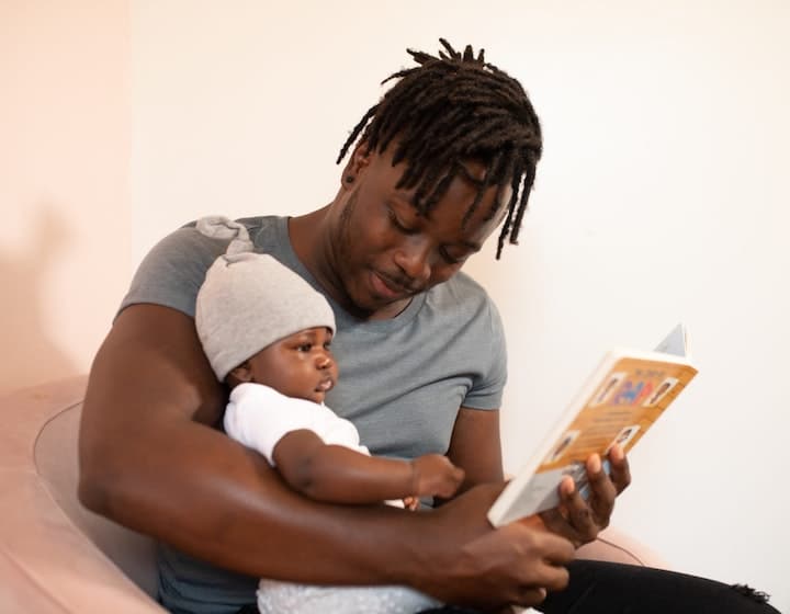 Dad reading a parenting book with his daughter