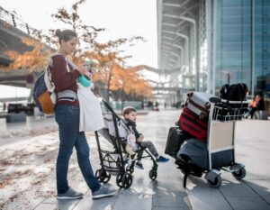 single mother travels with baby in carrier, toddler in stroller and carry on luggage