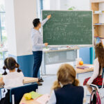 Maths tutor teaching a class of students with maths equations on a blackboard in Hong Kong