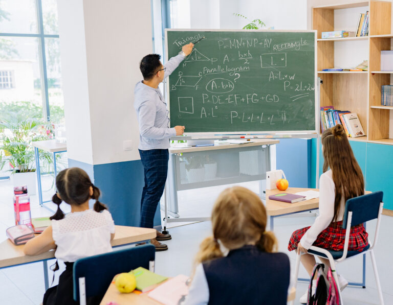 Maths tutor teaching a class of students with maths equations on a blackboard in Hong Kong