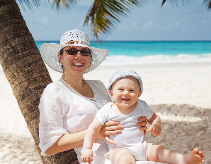 cute baby with mum on a tropical beach fighting jet lag after travel