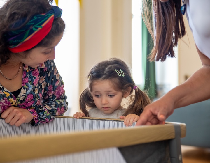 mum shows toddler her travel crib before travelling