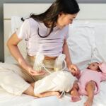 woman using a double breast pump next to her newborn baby at home in Hong Kong, where to buy breast pumps in Hong Kong from youha, medela, spectra, haakaa, baby buddha and more