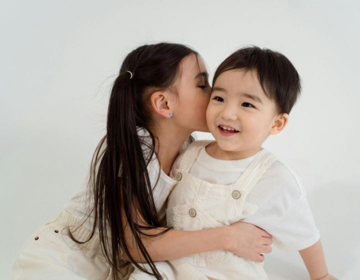 Signs Your Kid is Up to No Good whispering into siblings' ears