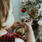 Little girl putting a Christmas ornament on a tree, where to get Christmas decorations in Hong Kong