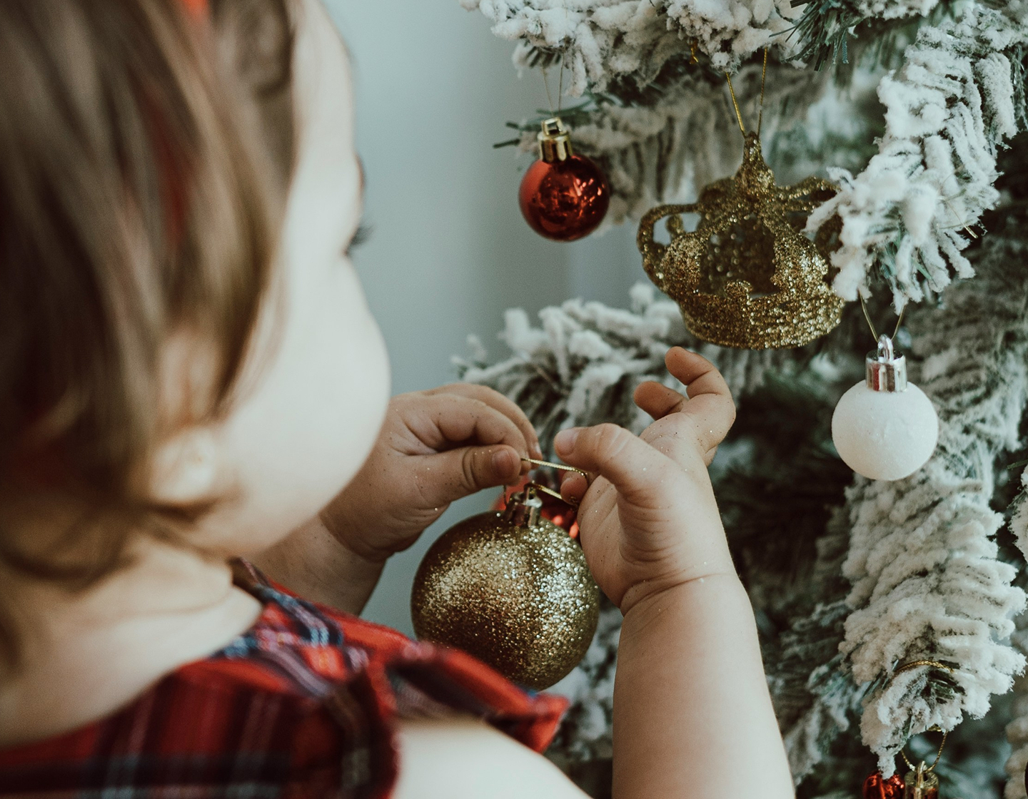 Little girl putting a Christmas ornament on a tree, where to get Christmas decorations in Hong Kong