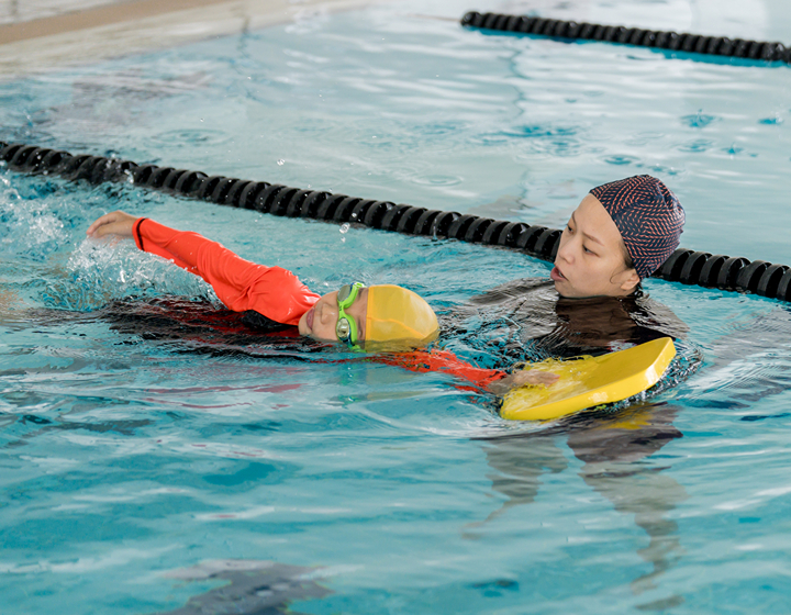 coach teaching a child how to swim at esf explore, best swimming classes for kids in hong kong, esf explore swim session