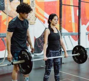 a personal trainer helping a woman lift weights at a hong kong gym