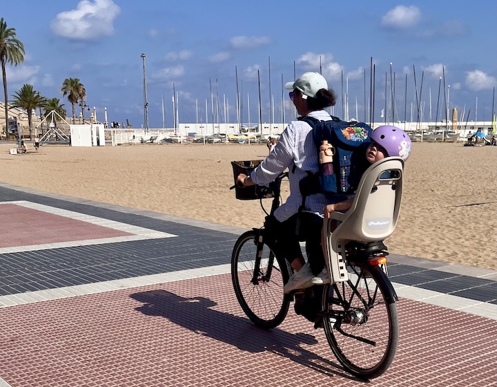 mother and child cycling on waterfront in Spain summer