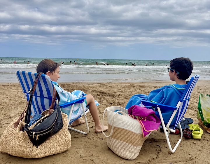 two boys sitting on the beach in Spain during summer