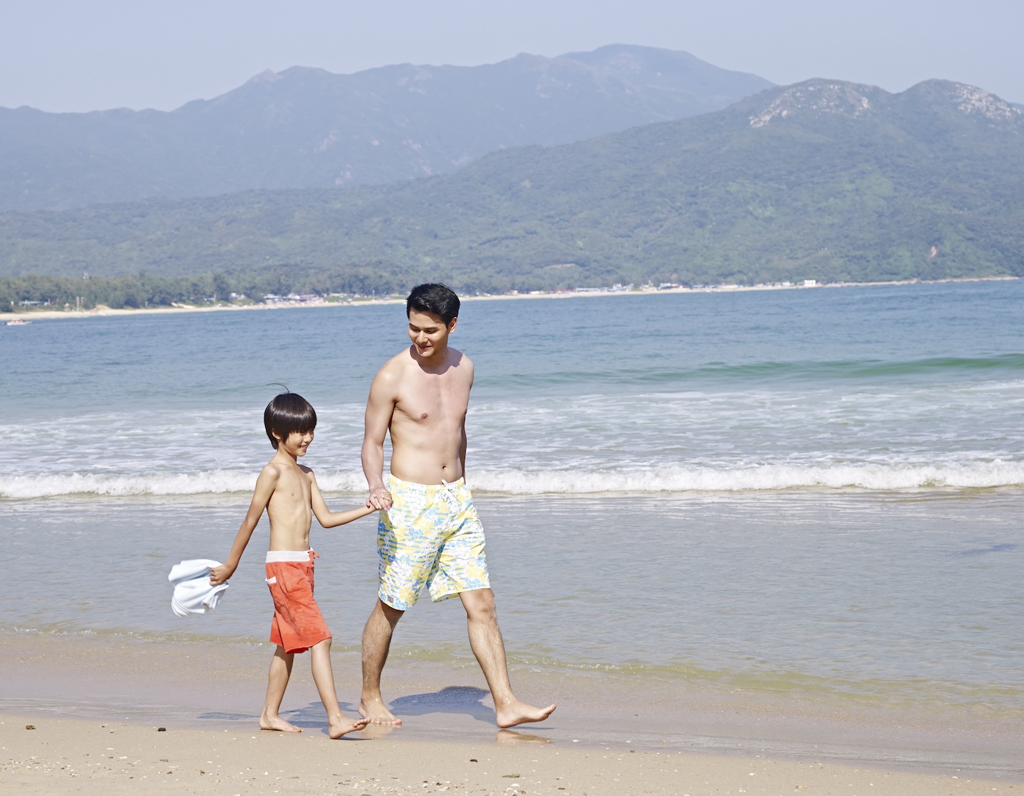 father and son walk along the beach in Hong Kong