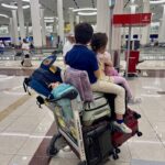 children riding suitcase trolley at airport