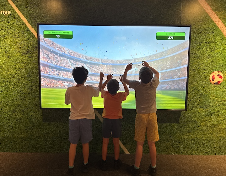 three boys play interactive games at the FIFA football museum in Hong Kong