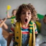 Boy cheering for Brazilian football team in the World Cup with family at home