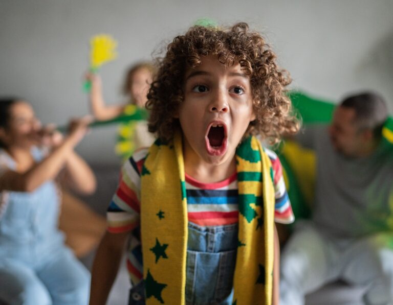Boy cheering for Brazilian football team in the World Cup with family at home