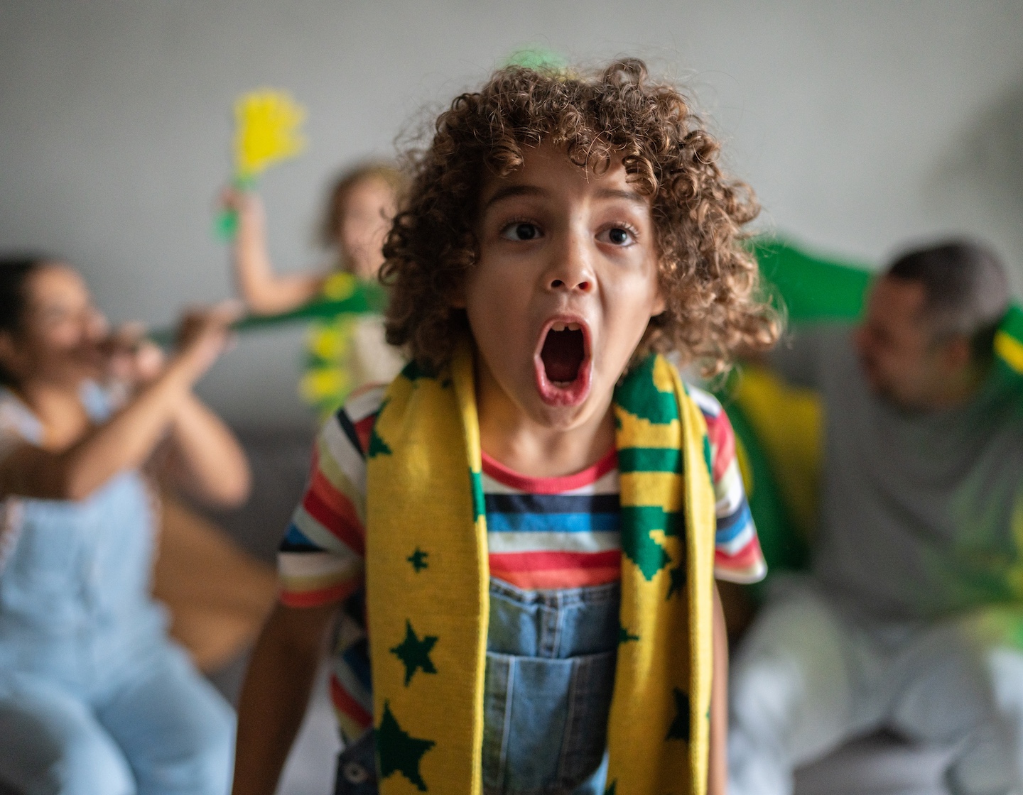 Boy cheering for Brazilian football team in the World Cup with family at home