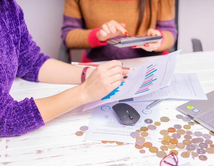 a woman in a purple jumper talks about her budget with her financial advisor