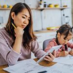 a mother sits next to her young daughter while looking at her financial plans