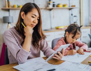 a mother sits next to her young daughter while looking at her financial plans