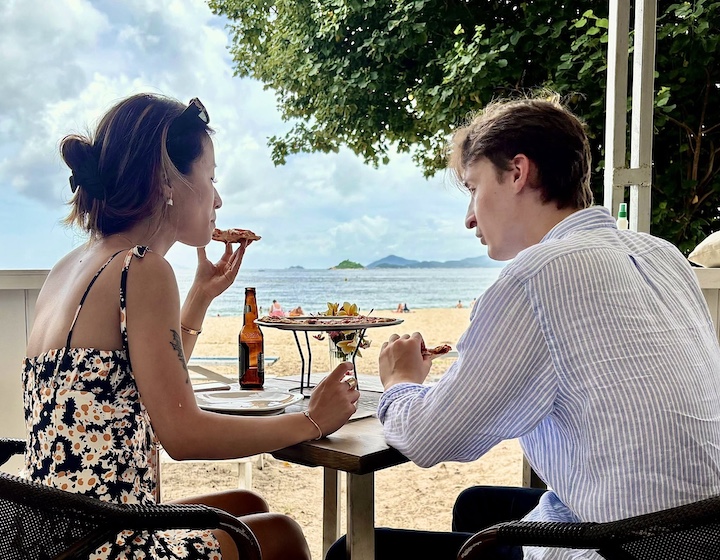 a couple eat pizza at lantana by Vicky restaurant at Chueng Sha beach