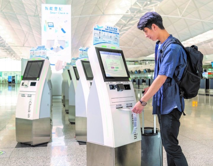 a man uses the self check in kiosks at Hong Kong international airport departures