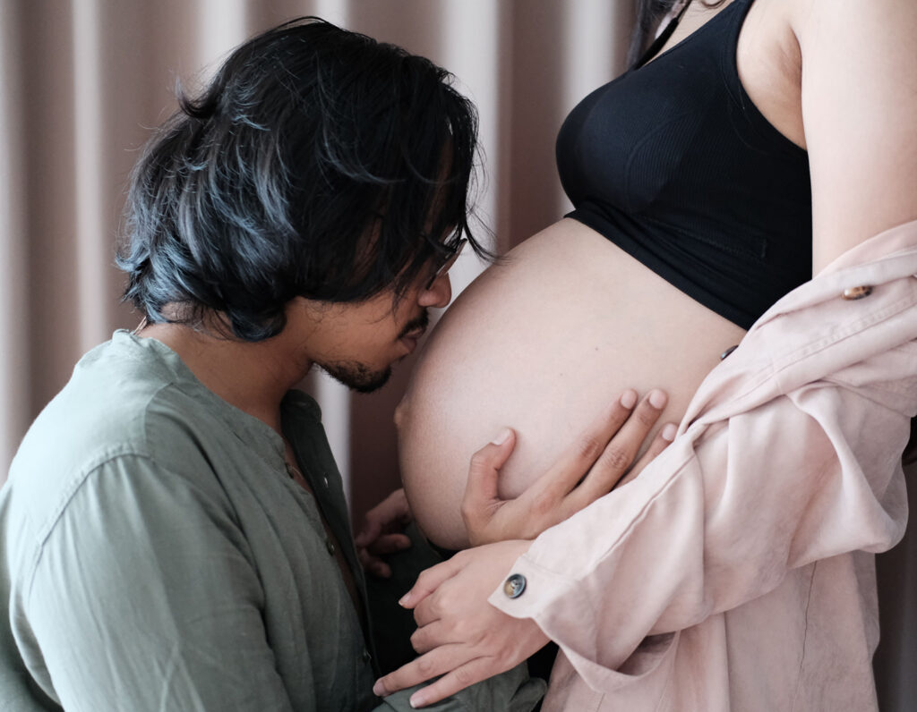 man kissing pregnant stomach; what fathers can do to support pregnancy and fertility success