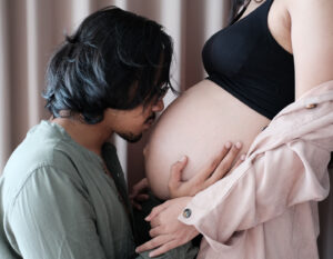 man kissing pregnant stomach; what fathers can do to support pregnancy and fertility success