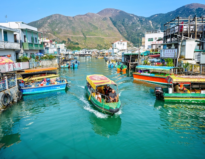 a boat cruises past stilt houses along the canals of Tai O fishing village in Hong Kong