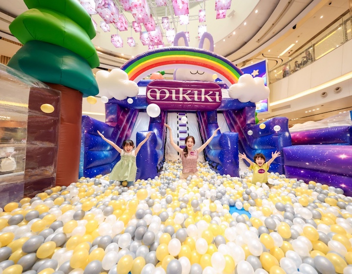 mother and children play in a ball pit in front of an inflatable slide at mikiki x momoland kids activity