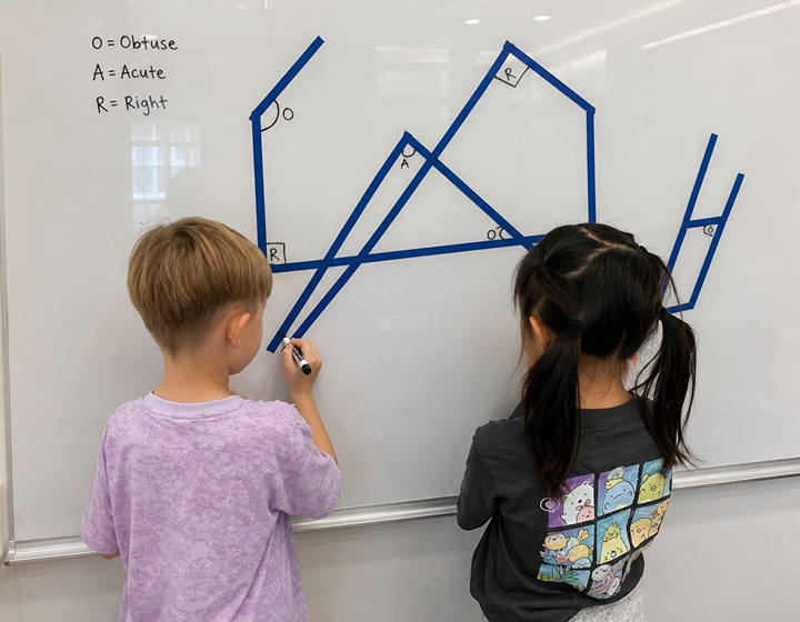 two students at a whiteboard in a Growing IQ class in Hong Kong learning about Geometry in tailored small group sessions
