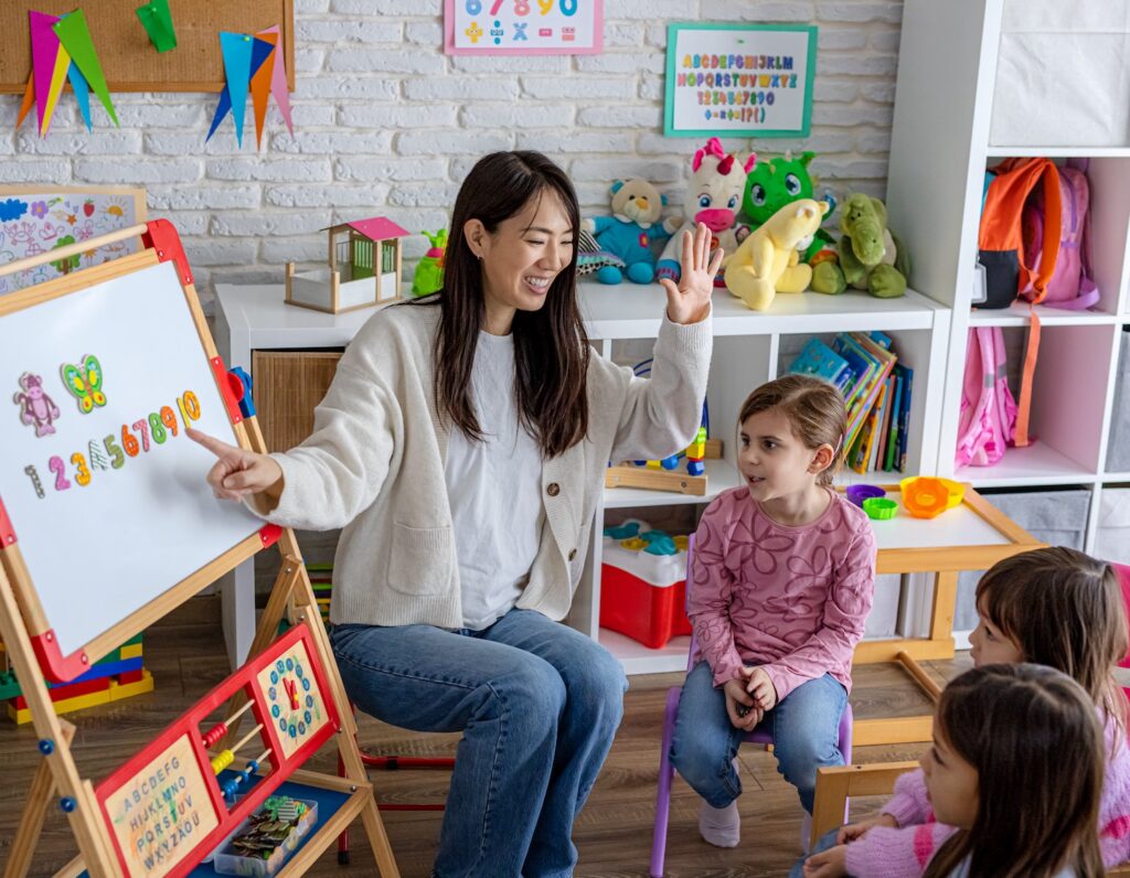 A preschool teacher introduces basic numbers to a group of young children during an interactive classroom learning activity in a Hong Kong bilingual playgroup or kindergarten.