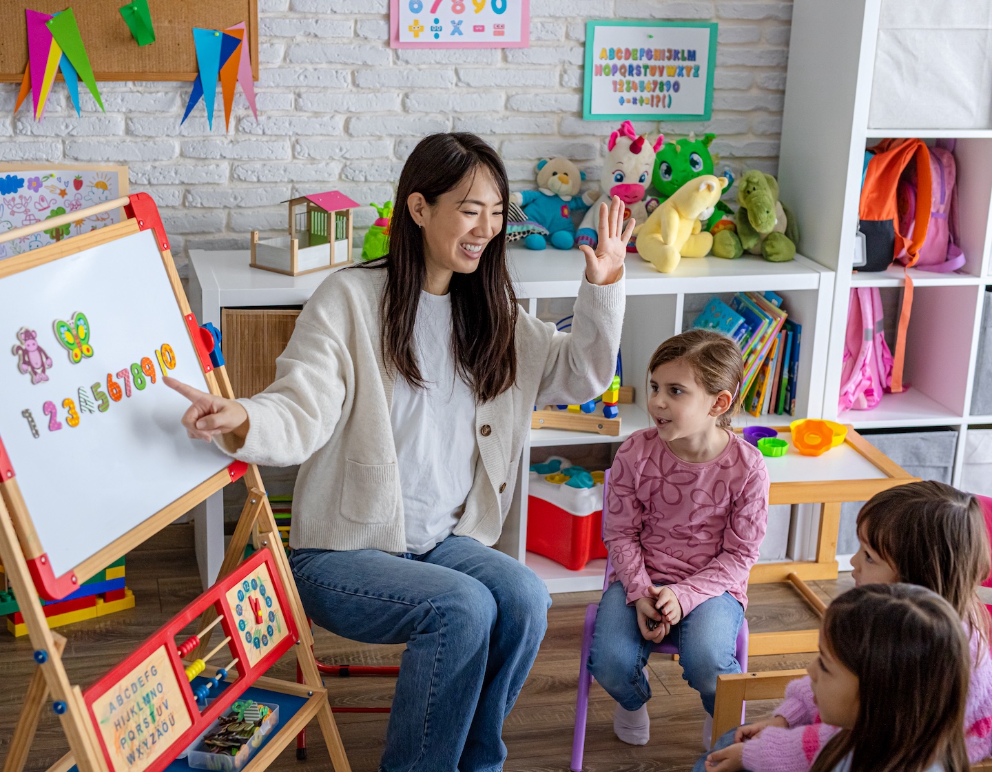 A preschool teacher introduces basic numbers to a group of young children during an interactive classroom learning activity in a Hong Kong bilingual playgroup or kindergarten.