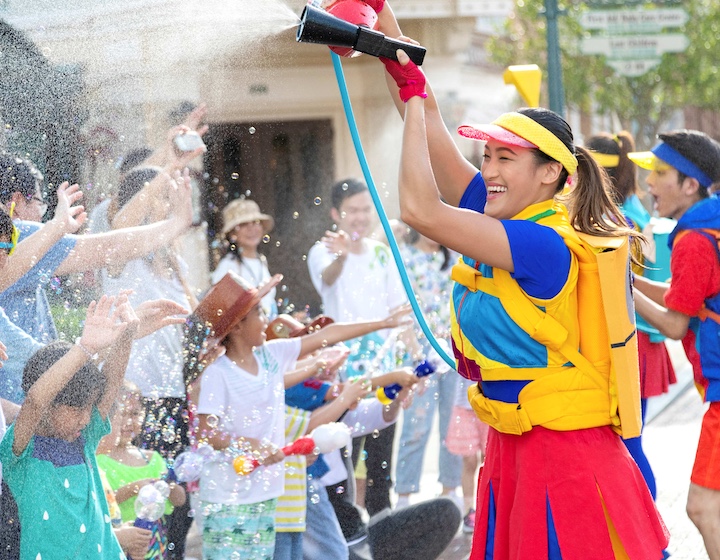 a Hong Kong disneyland performer sprays the crowd in summer