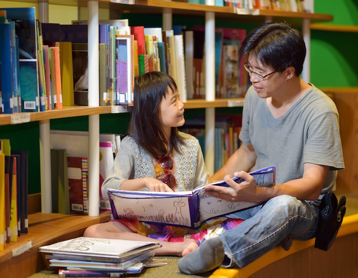 father and daughter read at a Hong Kong public library on a rainy day in hong kong