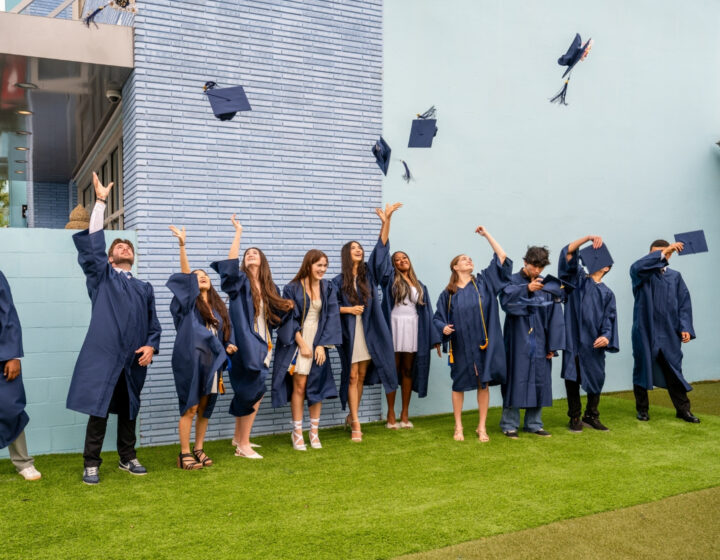students at Crimson Global Academy celebrate their graduation by throwing their caps in the air.