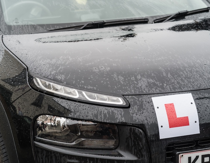 a black car displaying a learner license plate during a Hong Kong driving lesson