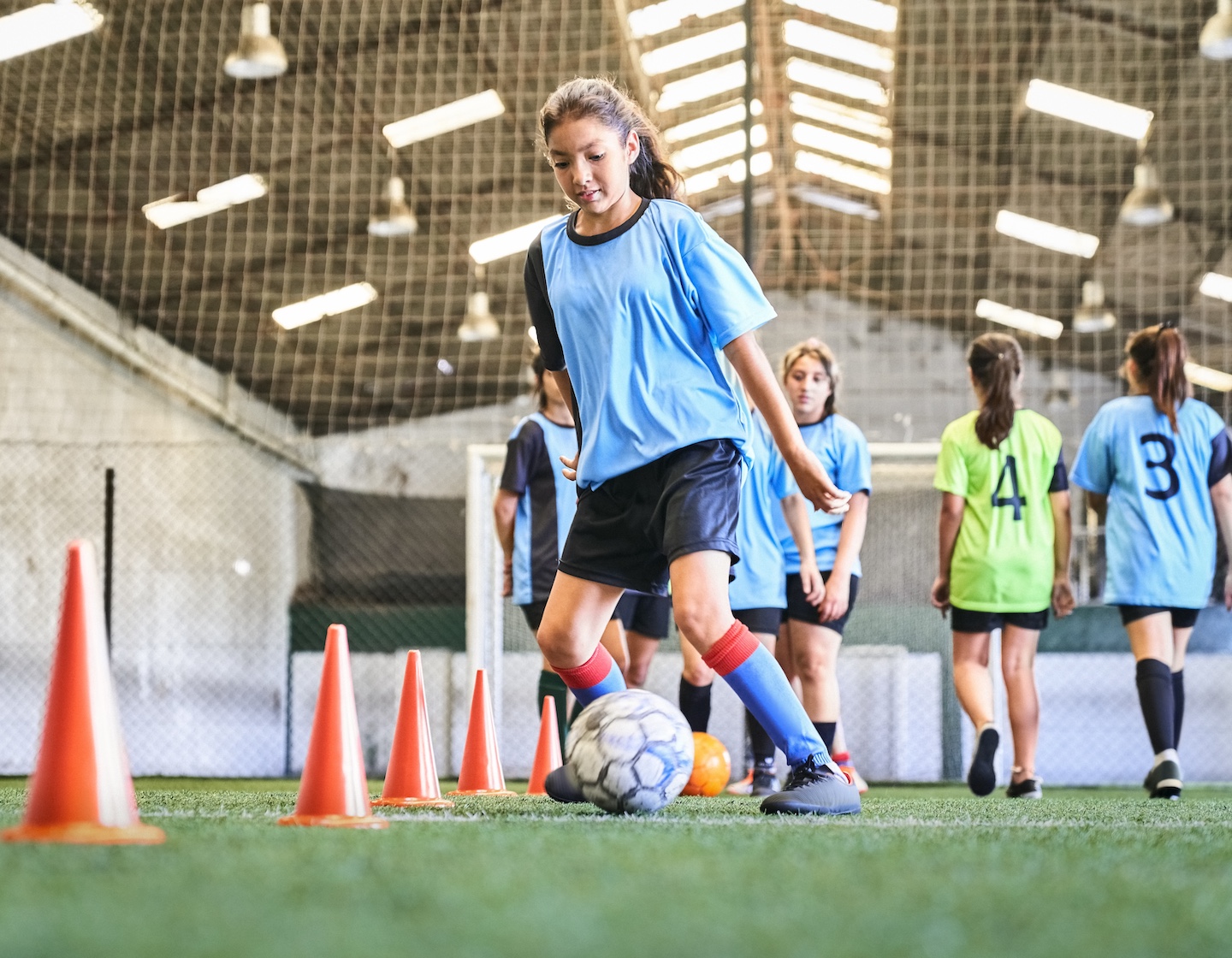 a teenage girls practices ball skills at a kids sports class