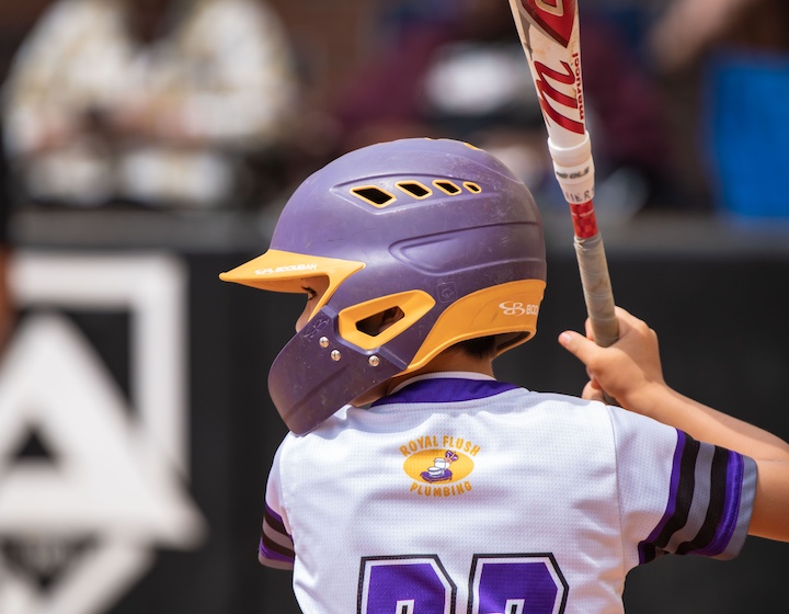 a young boy in a purple helmet plays baseball in Hong Kong