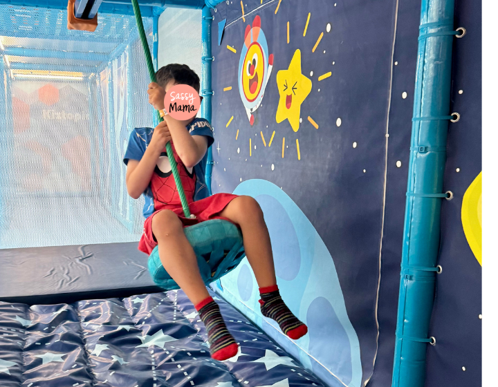 a boy with logo over face swings on a zipline at kiztopia in tseung kwan o