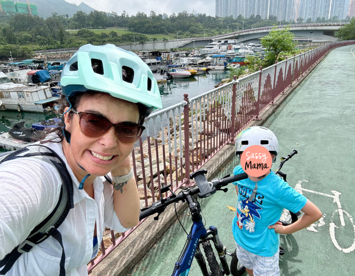 mother and son starting a bike ride along tseung kwan o cycling path with boats in the background