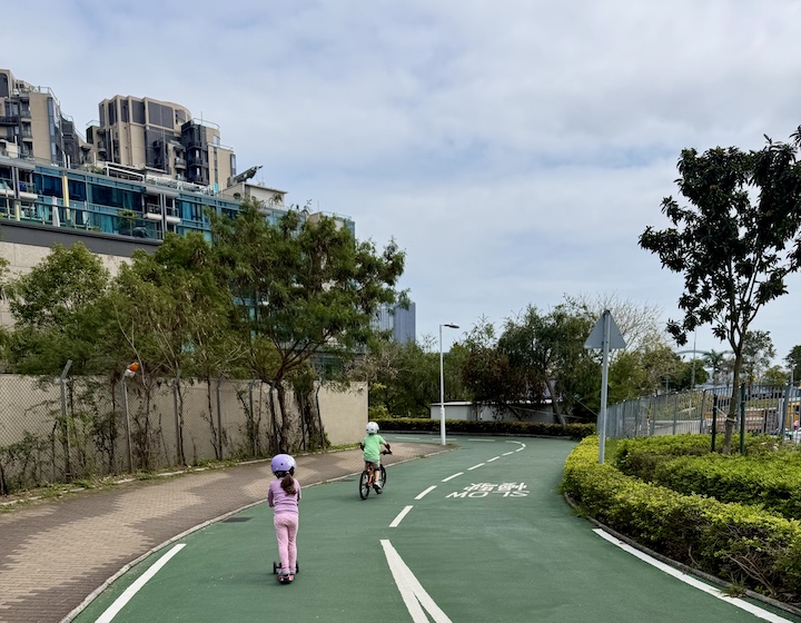 brother and sister scooter along tseung kwan o waterfront bike path