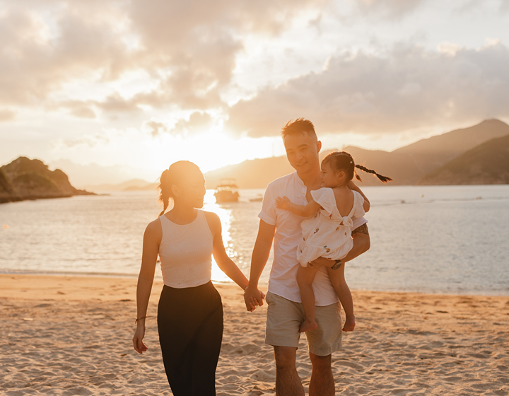 happy family on a beach in Hong Kong, standing in front of the water, photo taken by Yaping Liu Photography