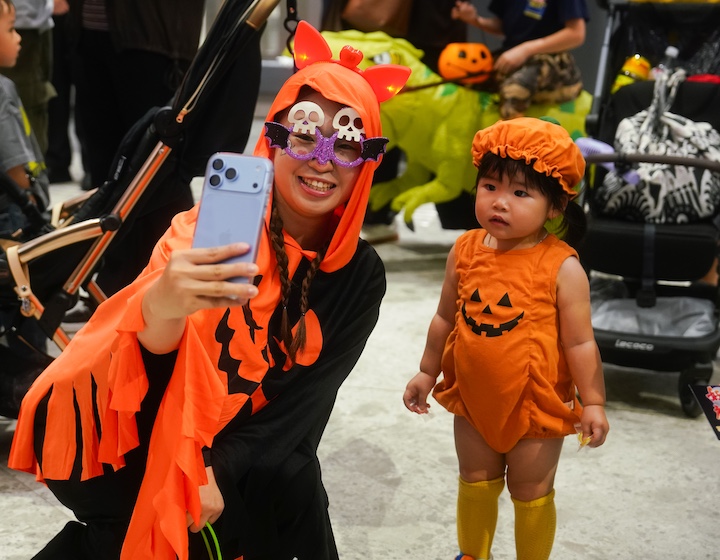 a halloween cosplay performer takes a photo with a toddler dressed as a pumpkin for halloween in Hong Kong 2026