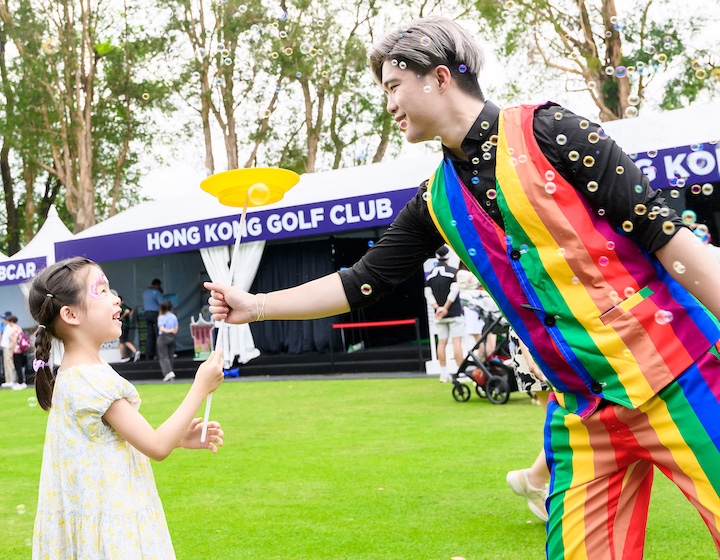 A girl interacts with a performer at the Hong Kong Jockey Club Fan Village for Link Hong Kong Open golf tournament