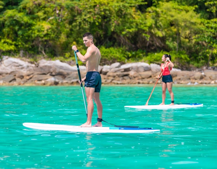 two teenager stand up paddle boarding at least Meridien beachfront resort phuket
