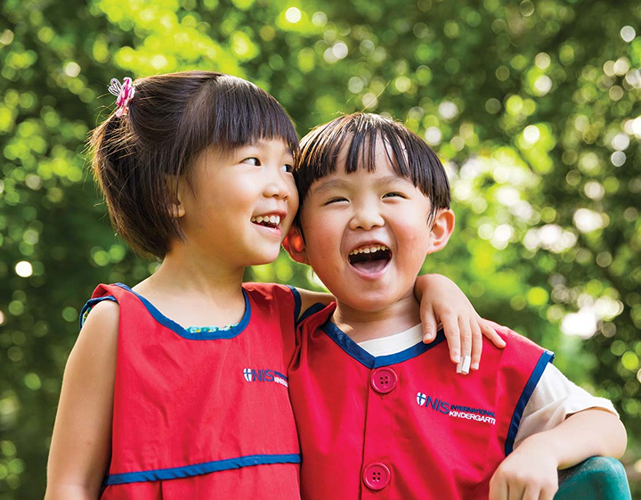 two students smiling and laughing together at Norwegian International School