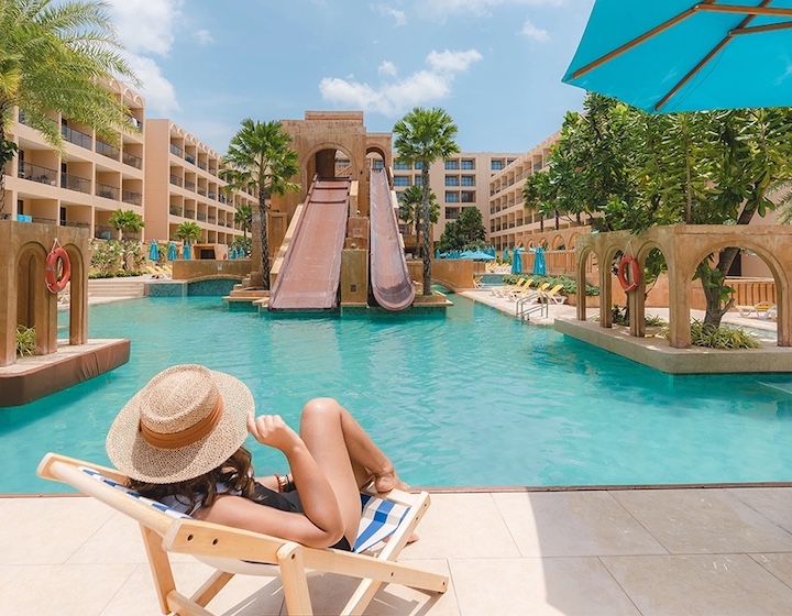 a woman relaxes by the pool and waterslides at pamookkoo resort phuket